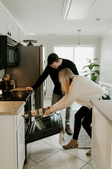 Two people adding food to the oven
